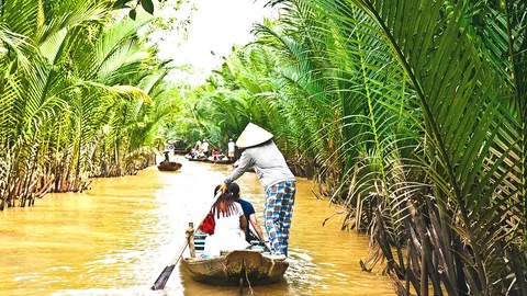 Reisende auf einem Ruderboot im Mekong Delta