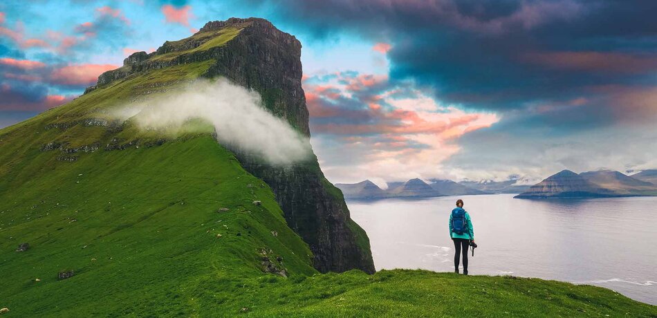 Frau genießt die Aussicht von den Klippen auf den Färöer Inseln