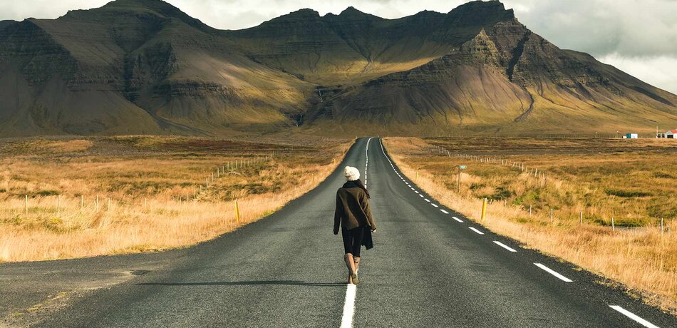 Frau spaziert entlang einer Straße in Island