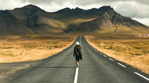 Frau spaziert entlang einer Straße in Island