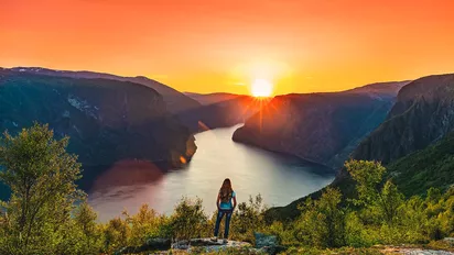 Eine Frau blickt in den Sonnenuntergang am Aurlandsfjord
