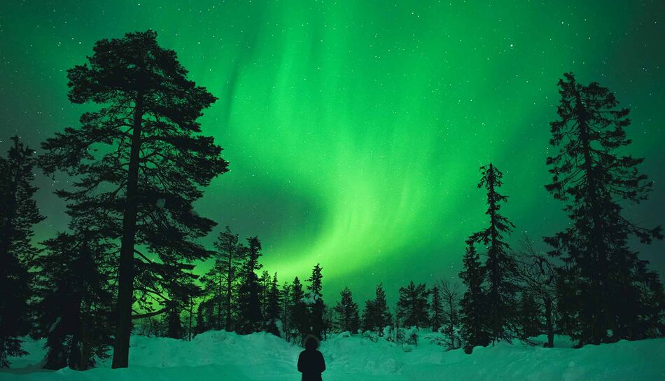 Ein Wanderer unter Nordlichtern in Levi in Lappland