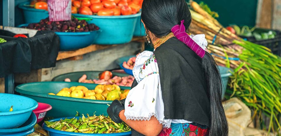 Eine Frau beim Bohnen sortieren auf dem Markt in Otavalo
