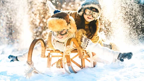 Zwei Kinder sitzen auf einem Schlitten in einer verschneiten Winterlandschaft